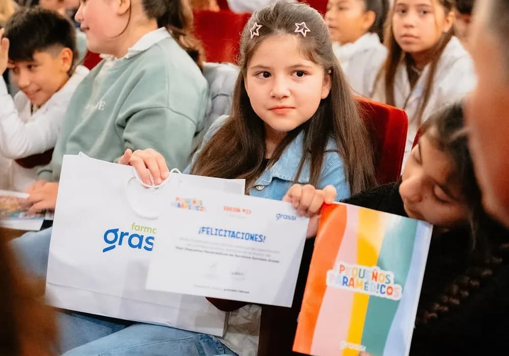 Una nena muestra su certificado de Pequeños Paramédicos entre sus compañeros
