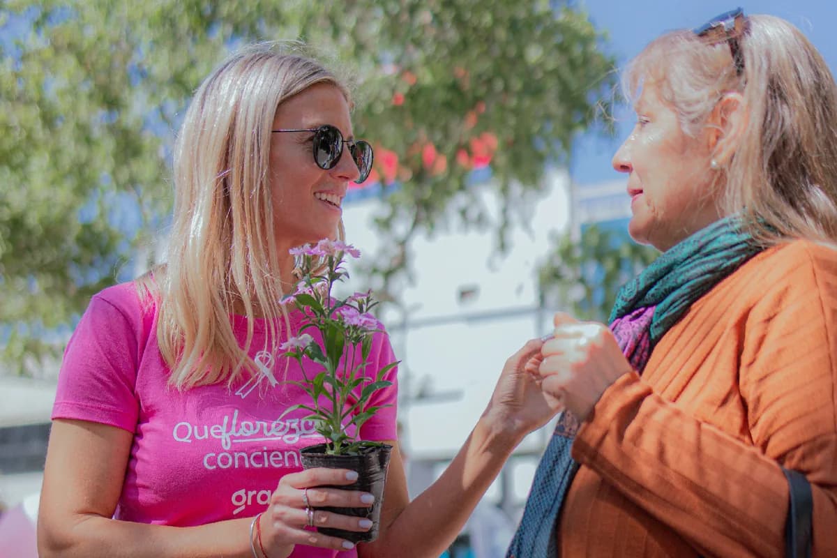 Una voluntaria entrega una planta durante una campaña de concientización en la vía pública