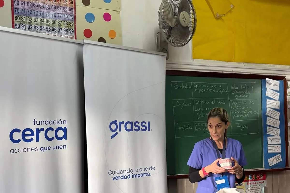 Charla sobre salud bucal en un aula, con banners de Fundación Cerca y Grupo Grassi