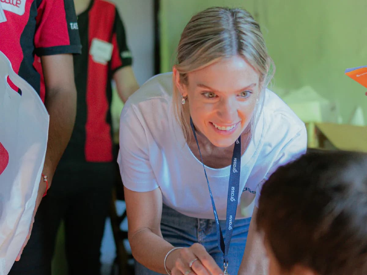 Una voluntaria de la fundación entrega una bolsa con útiles a un nene en un merendero